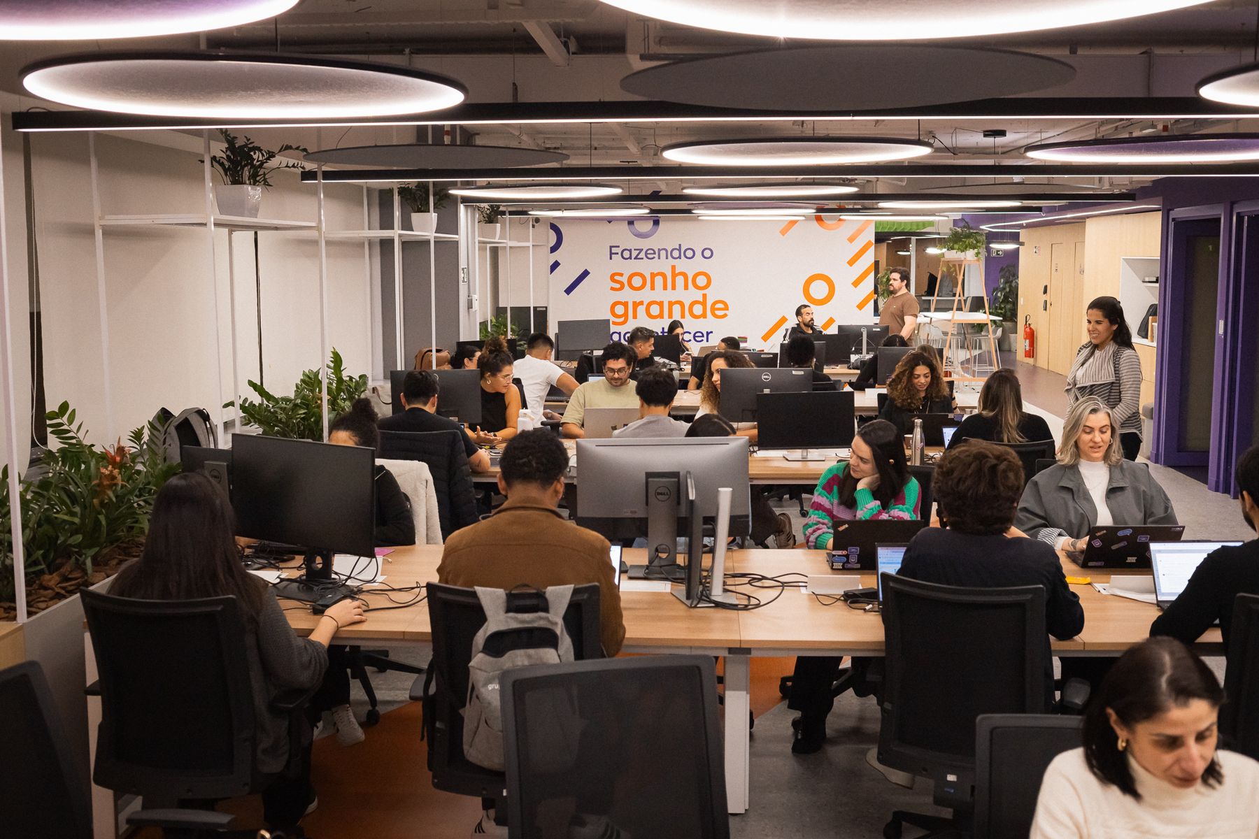 Andar de trabalho do Grupo OLX com várias pessoas nas mesas