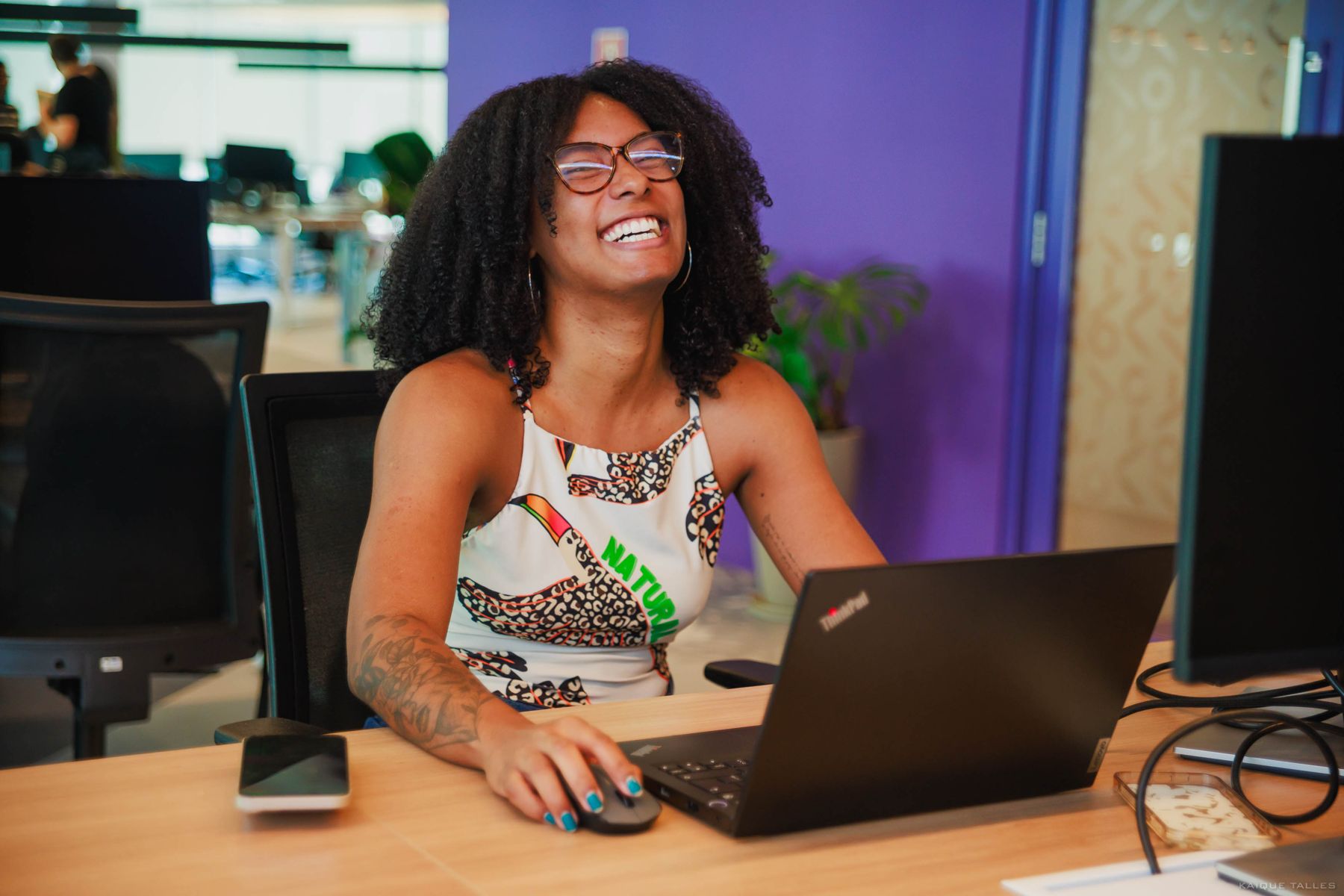 Mulher de óculos rindo diante de um notebook